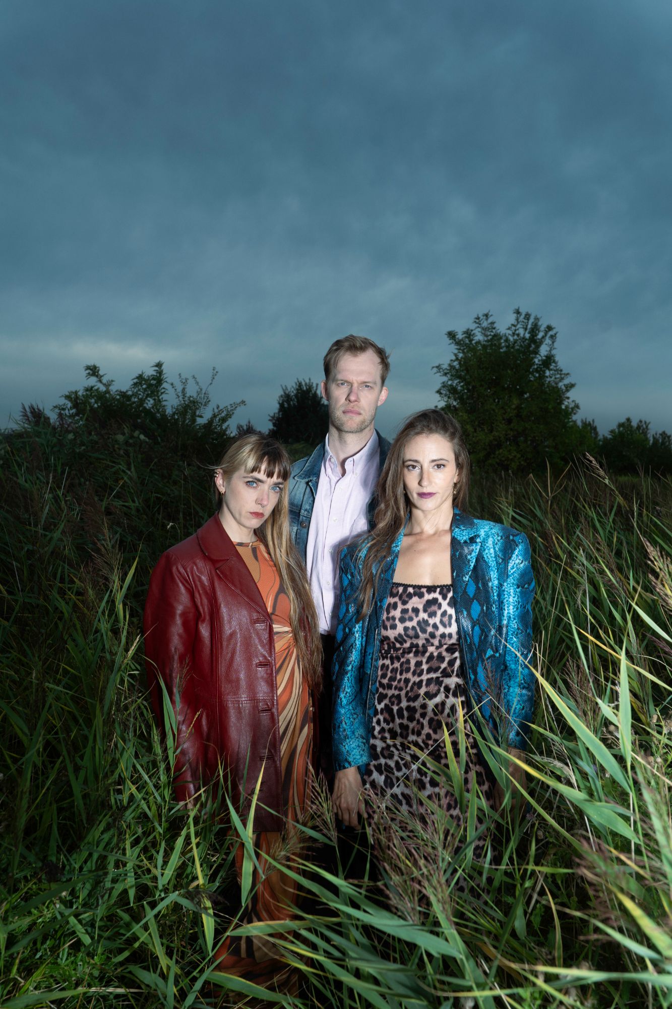 Three members of Chapter 58 standing close together in tall reeds under a stormy blue sky.