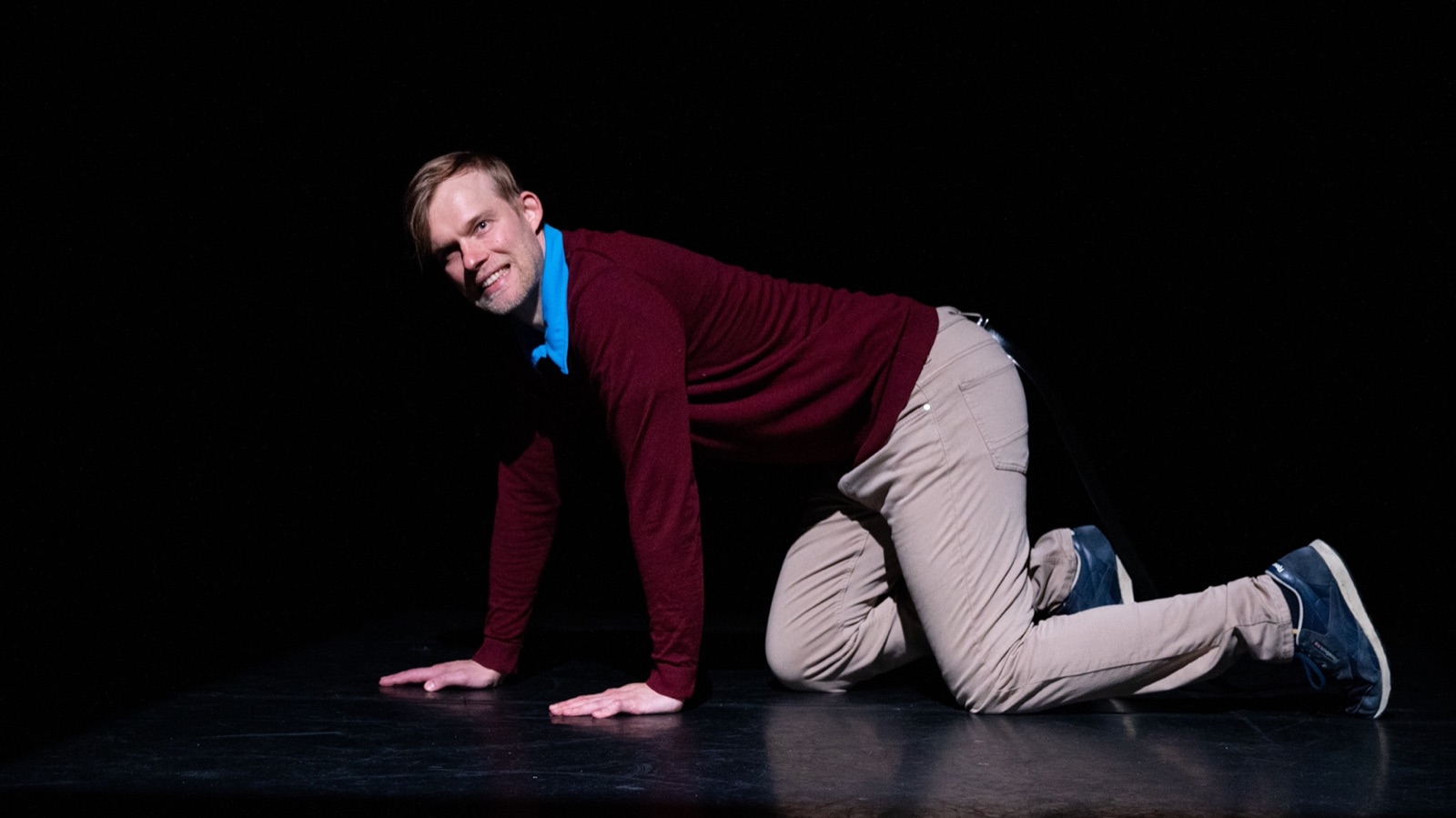 Antti Uimonen crawling on all fours, smiling directly at the camera, full body in frame.