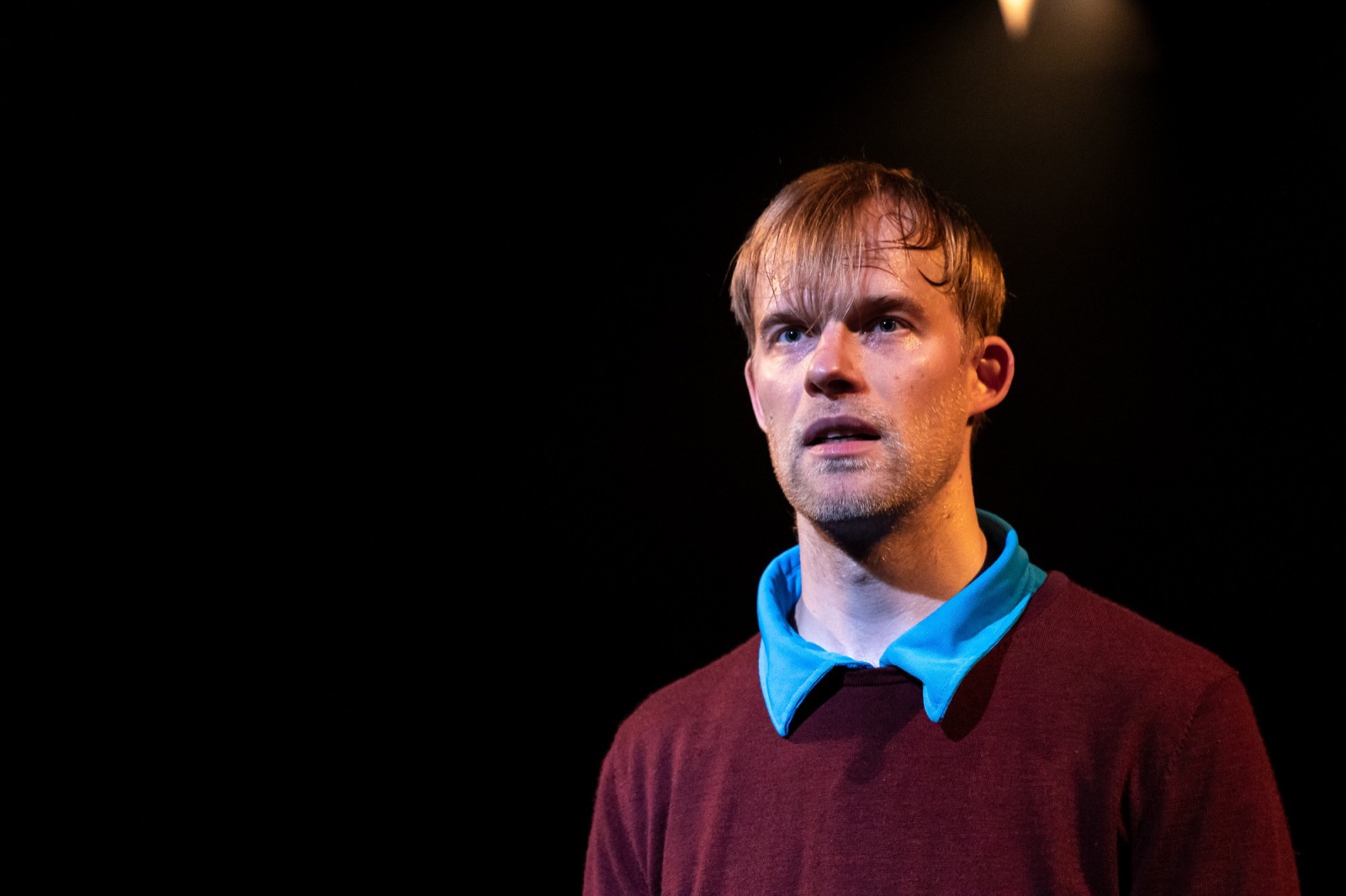Close-up of Antti Uimonen's face and shoulders, warmly lit on a dark stage.